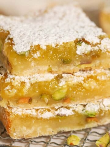 Stack of three lemon pistachio bars on a wire rack.