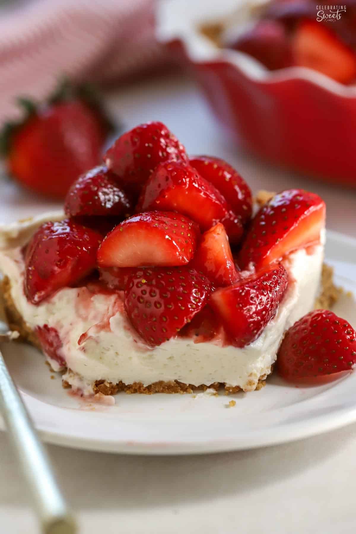 Strawberry cream cheese pie topped with fresh strawberries on a white plate.