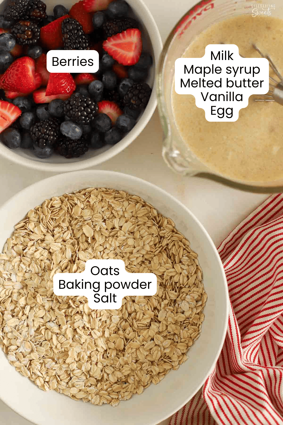A white bowl filled with oats, a white bowl filled with mixed berries, and a glass measuring cup filled with milk.