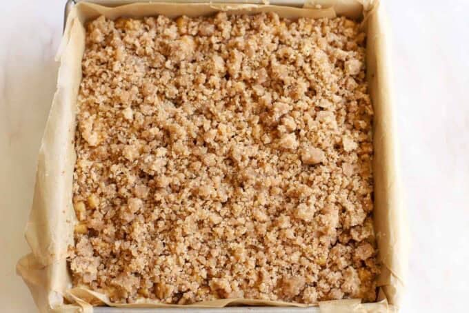 Crumb-topped cheesecake in a square pan.