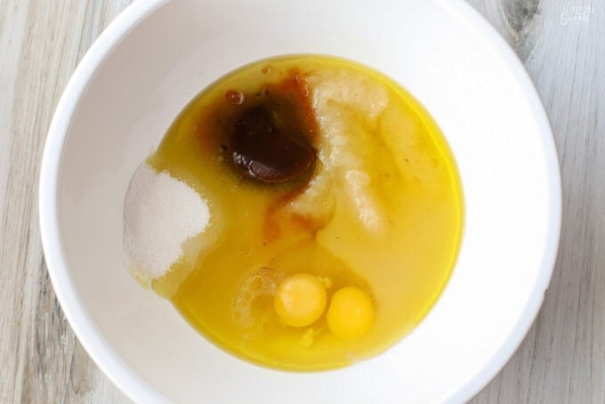 Sugar, oil, eggs, applesauce in a large white bowl.
