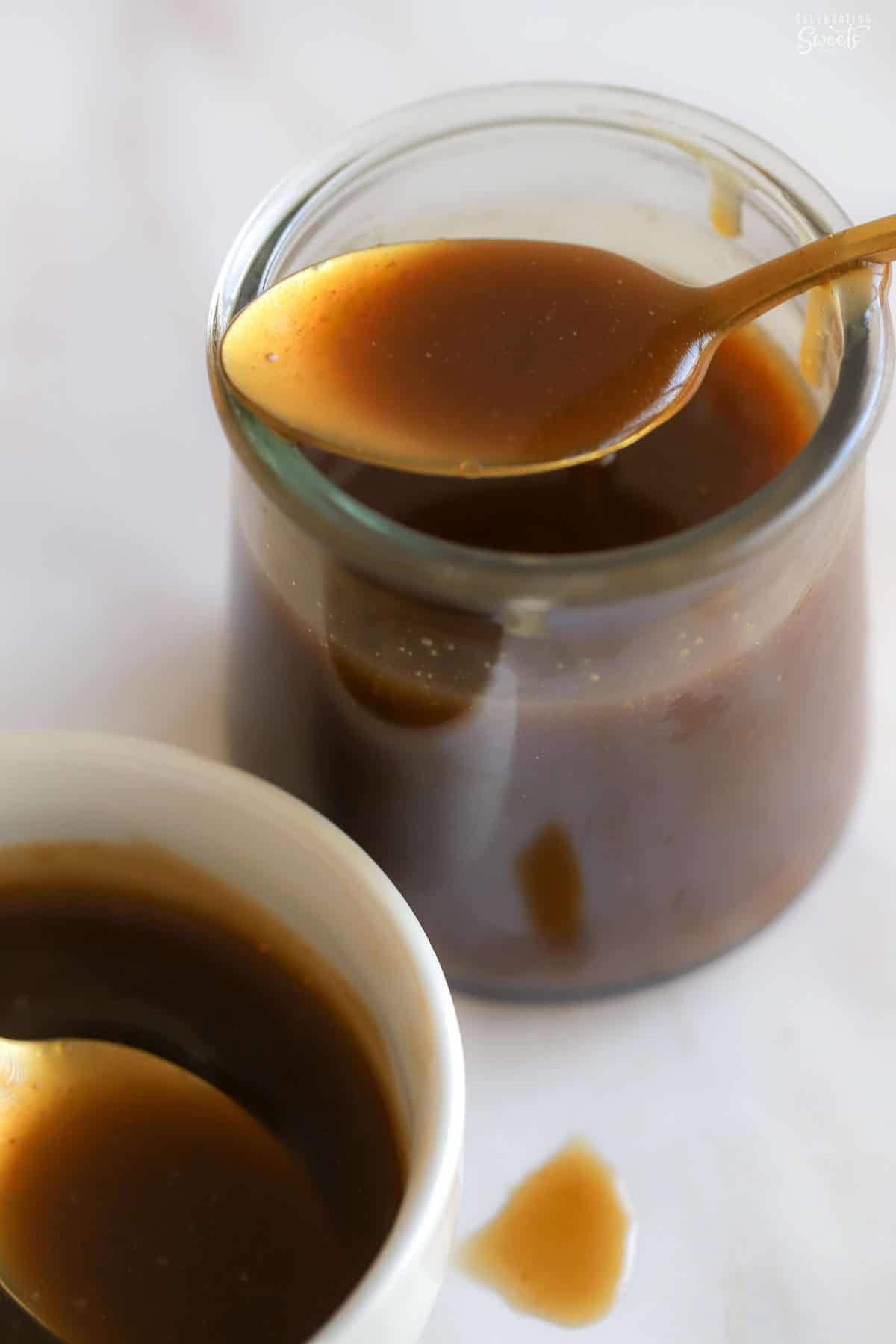 Toffee sauce in a glass jar with a gold spoon on top.