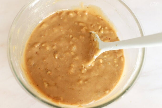 Blondie batter filled with chopped walnuts in a glass bowl.