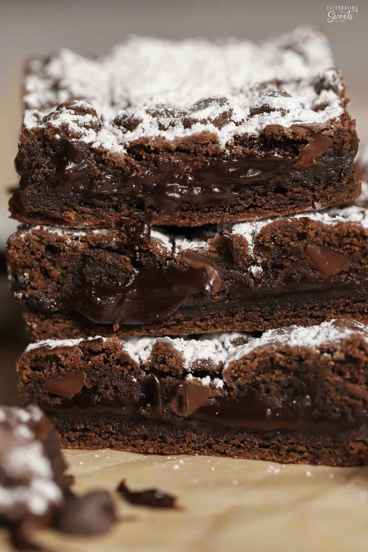 Stack of three chocolate cookie bars topped with powdered sugar.