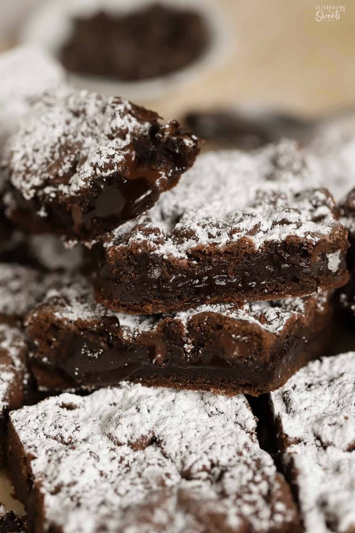 Chocolate cookie bars topped with powdered sugar piled on a piece of parchment paper.