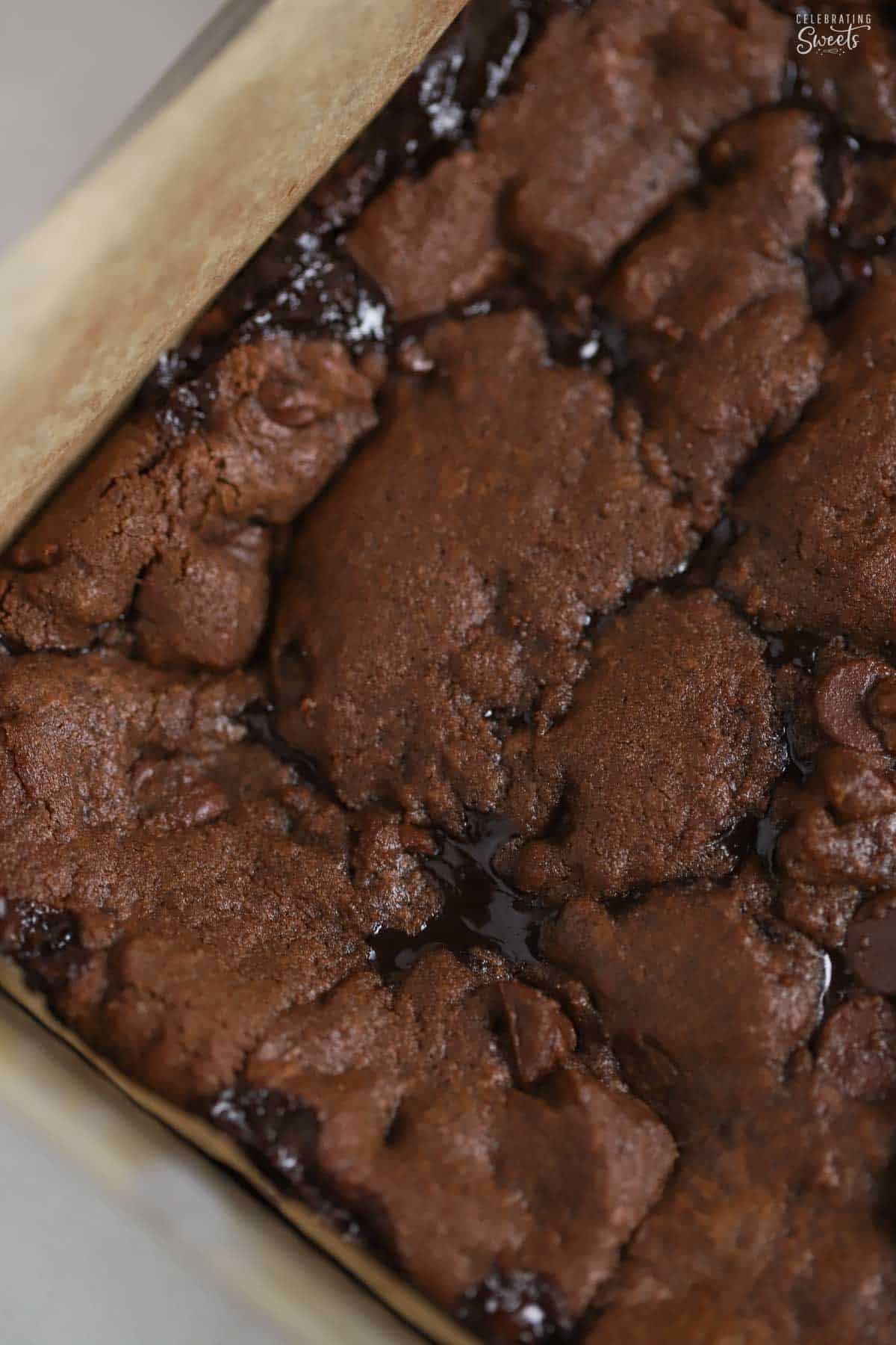 Chocolate cookie bars with fudge filling in a parchment-lined baking dish.