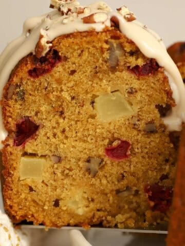Closeup of a slice of pumpkin bundt cake filled with apples, cranberries, and pecans.