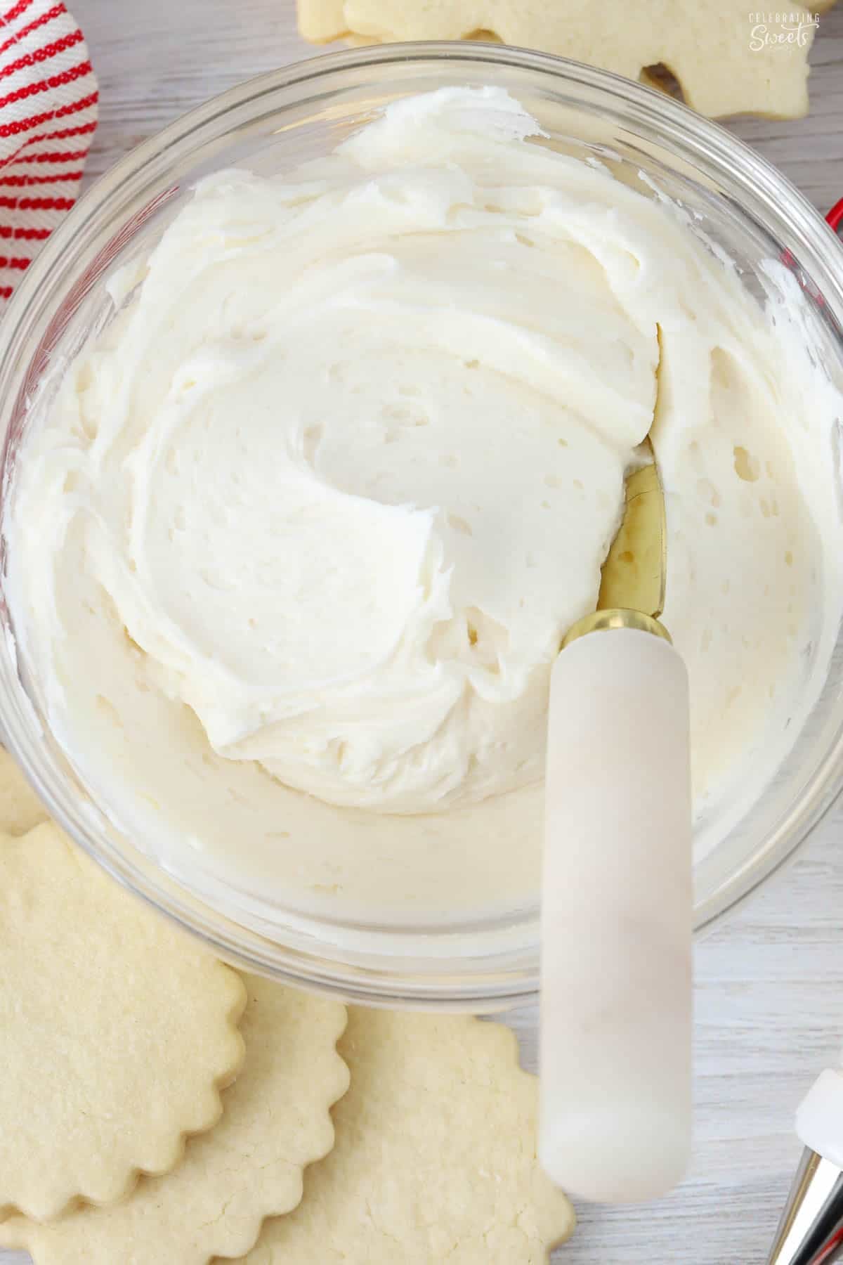 Sugar cookie frosting in a glass bowl with a marble and gold knife in it.