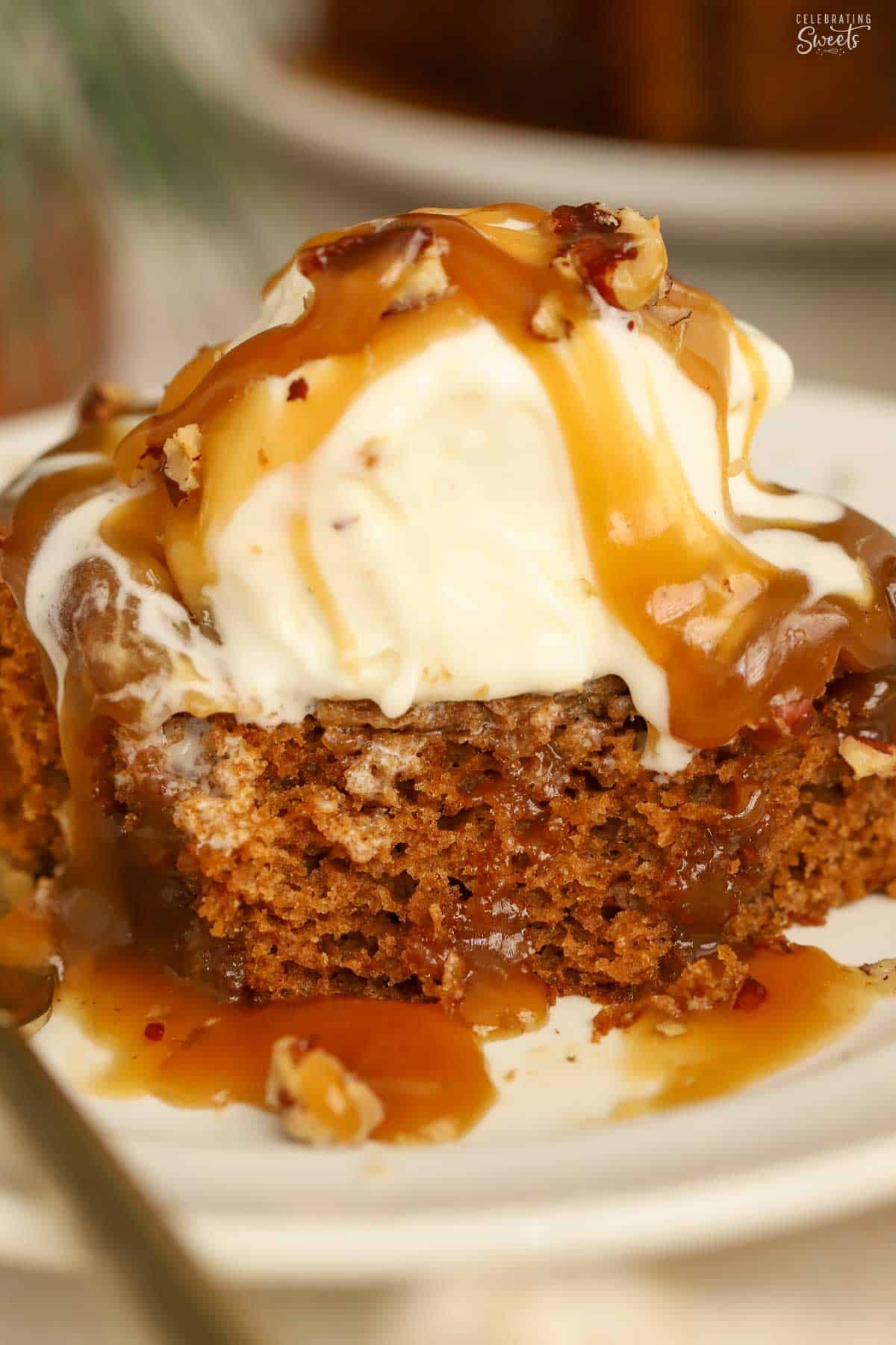 Slice of gingerbread cake topped with ice cream and toffee sauce.