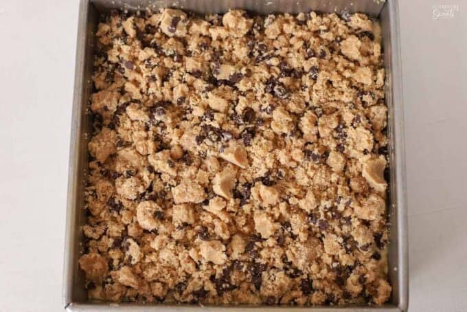 Unbaked chocolate chip crumb cake in a square metal pan.