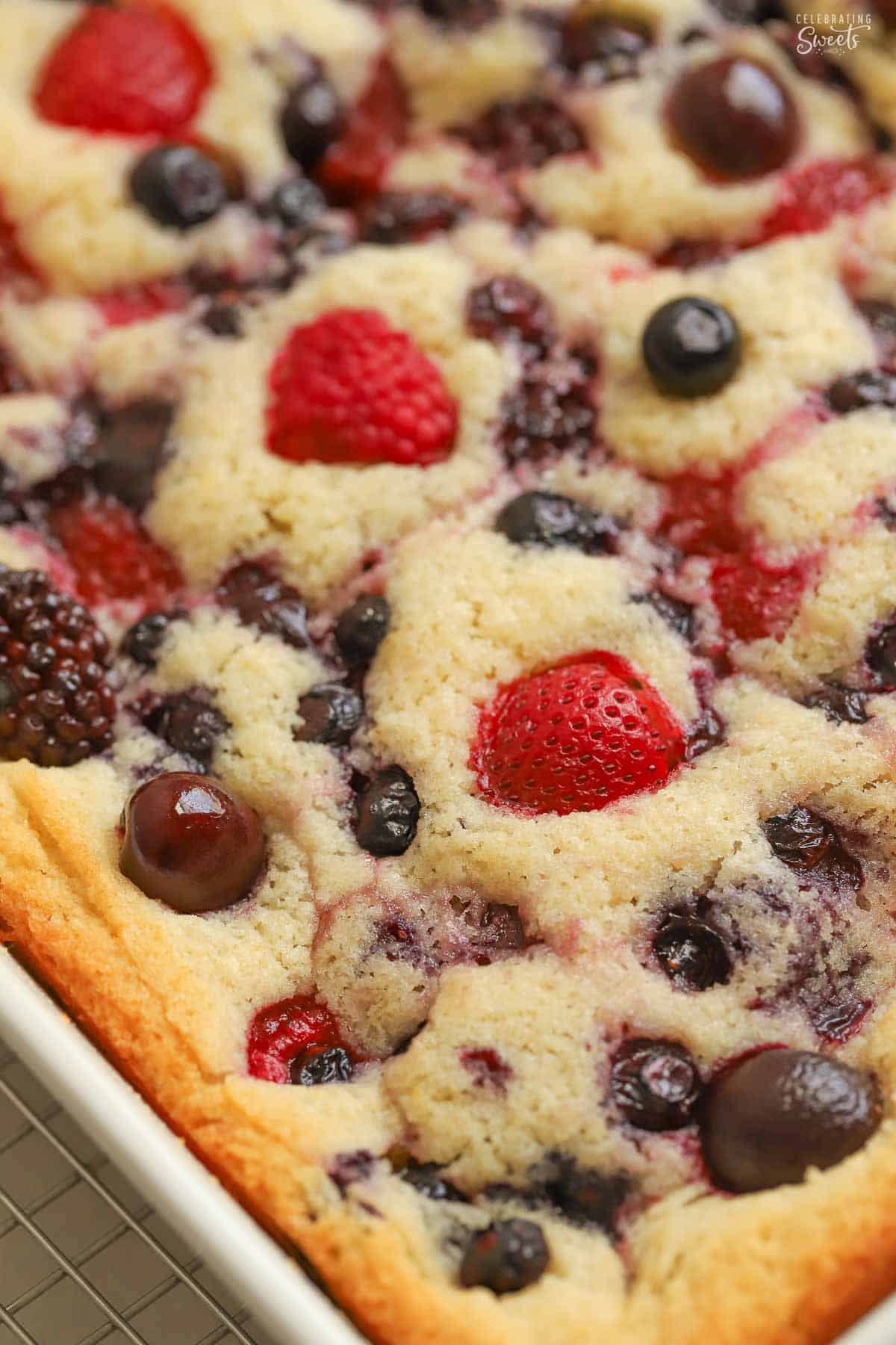 Cherry berry spoon cake in a white baking dish set on a wire rack.