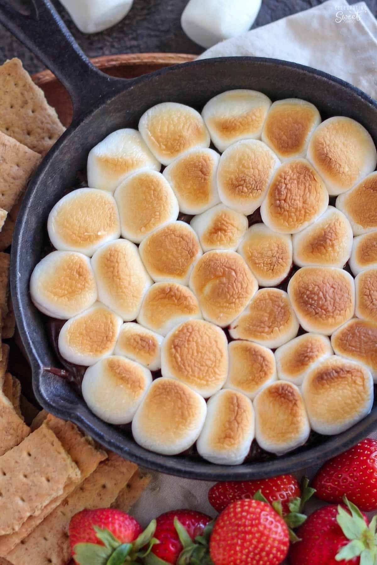S'mores dip topped with toasted marshmallows in a cast iron skillet.