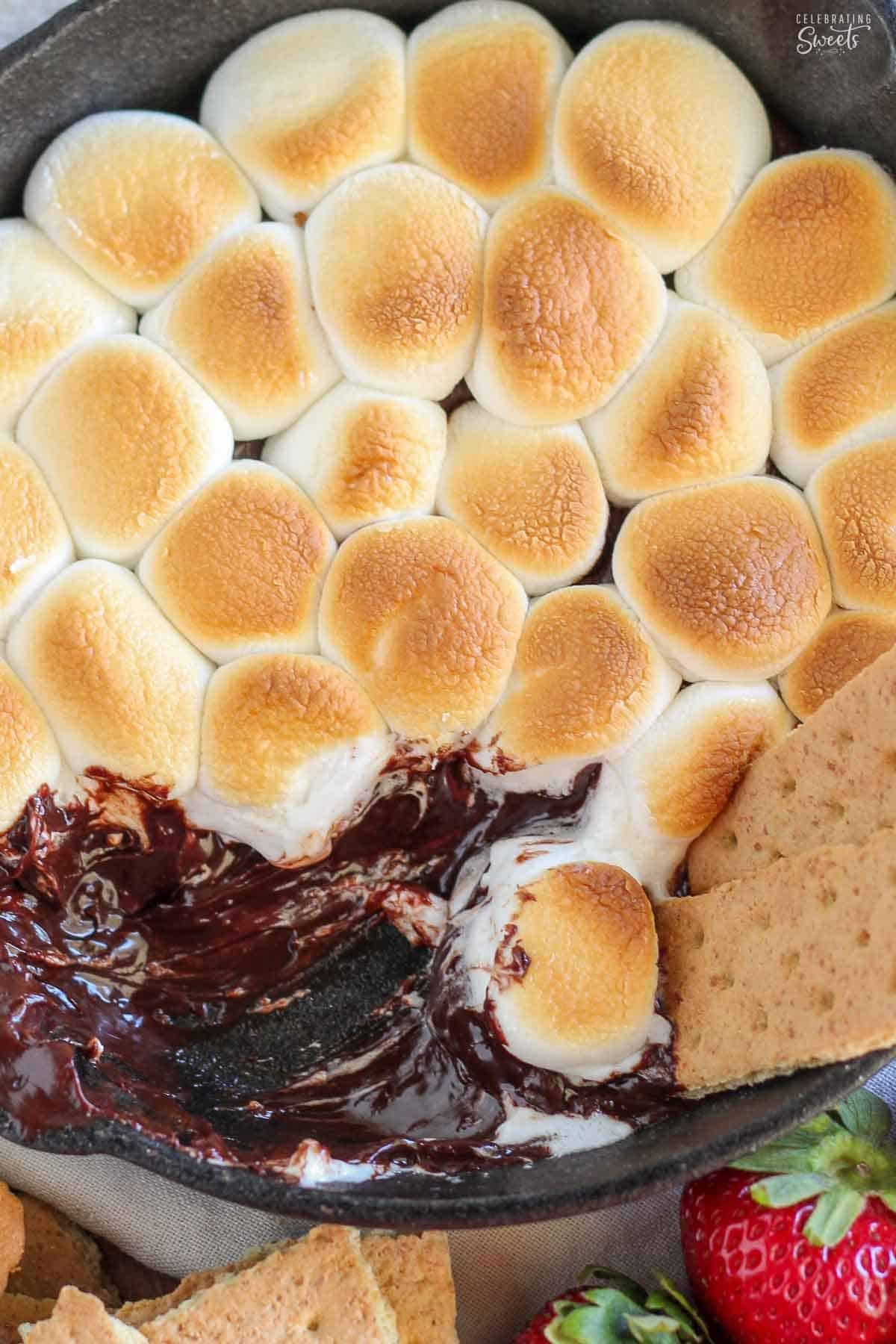 S'mores dip in a cast iron skillet with pieces of graham crackers in it.