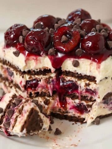 A slice of black forest icebox cake topped with cherries on a white plate.