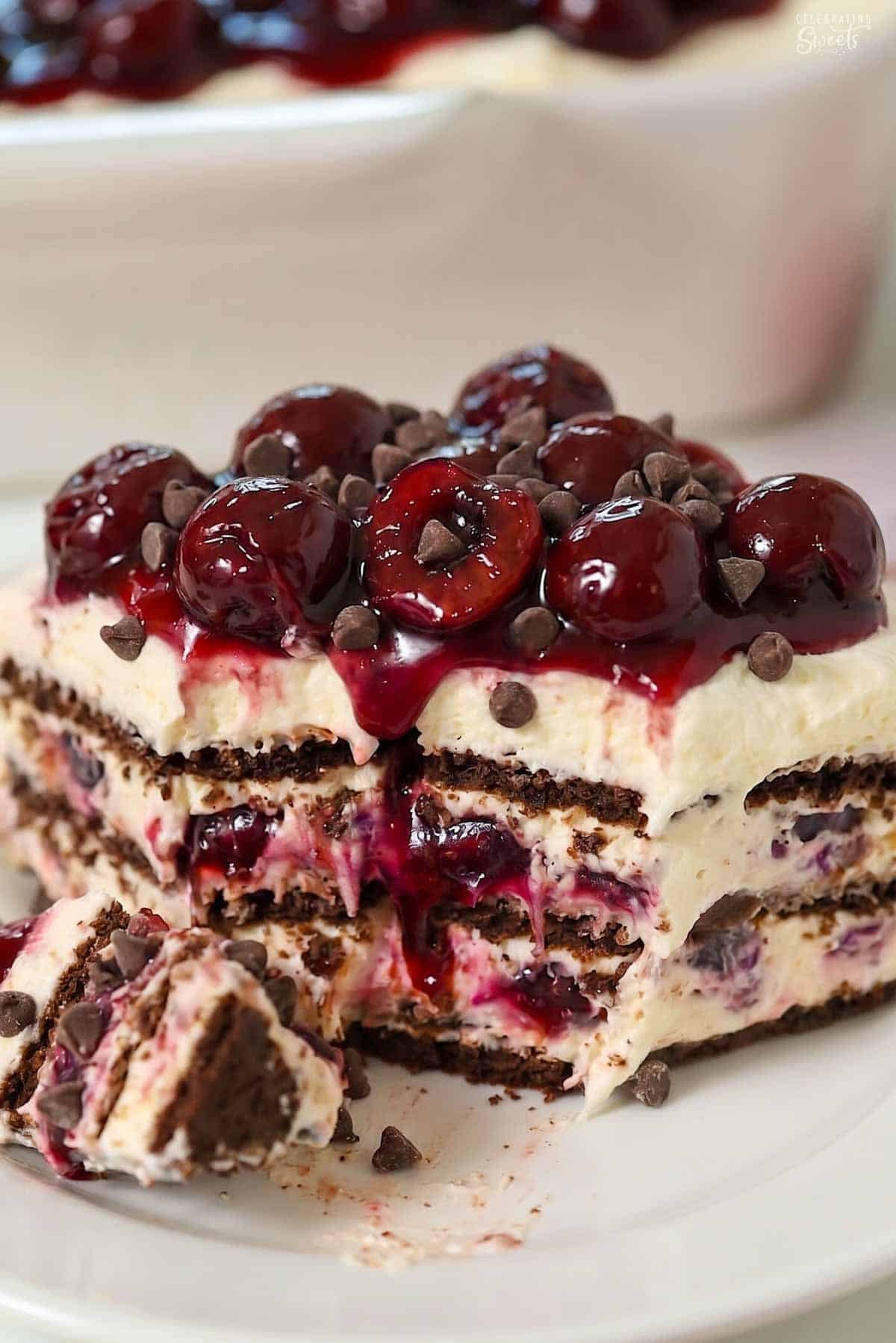 A slice of black forest icebox cake topped with cherries on a white plate.