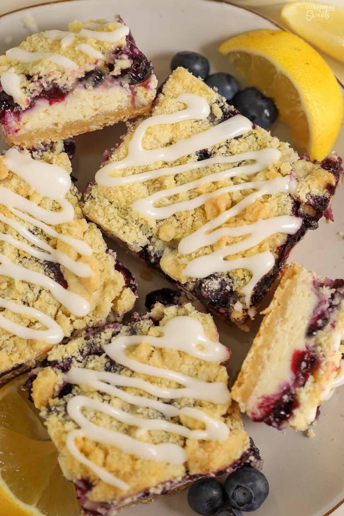 Lemon crumb bars drizzled with white icing on a white plate.