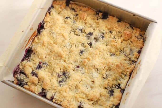 Lemon blueberry crumb bars in a parchment-lined square pan.
